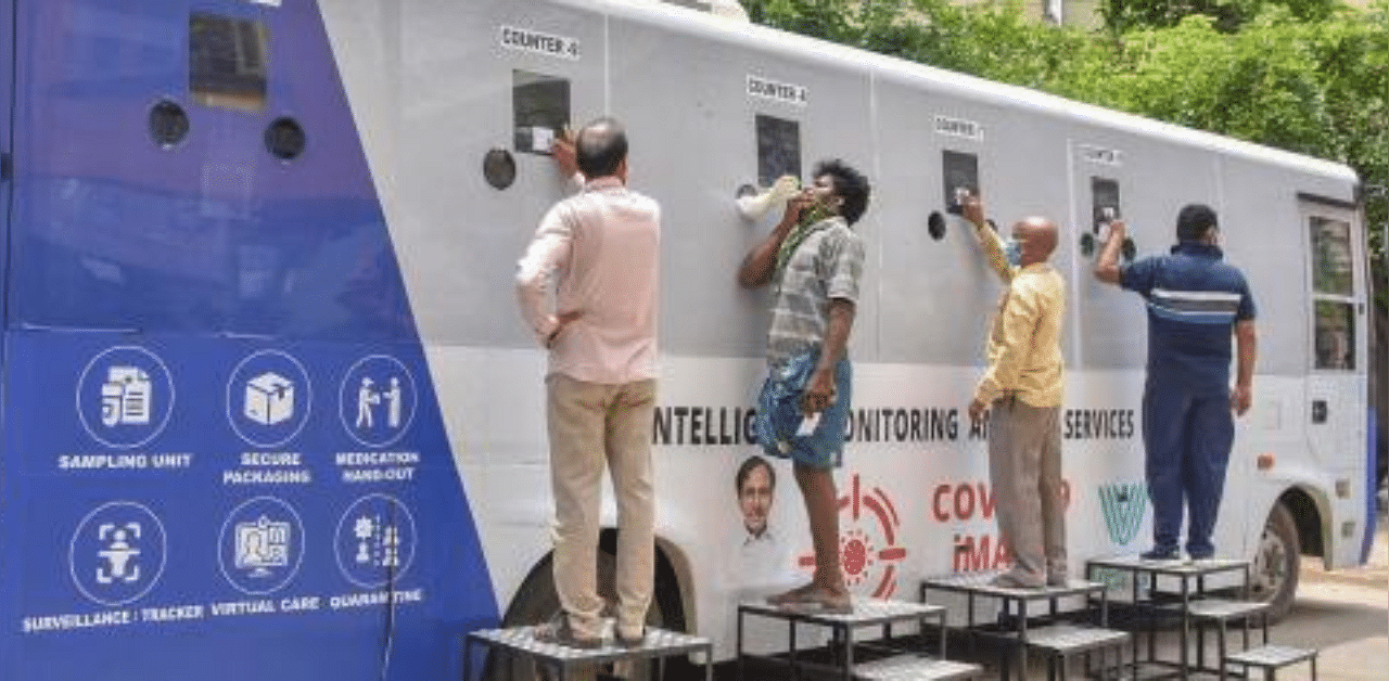 People stand near a Covid-19 mobile testing facility, at Jafarguda near Karwan in the old city of Hyderabad. Credit: PTI Photo
