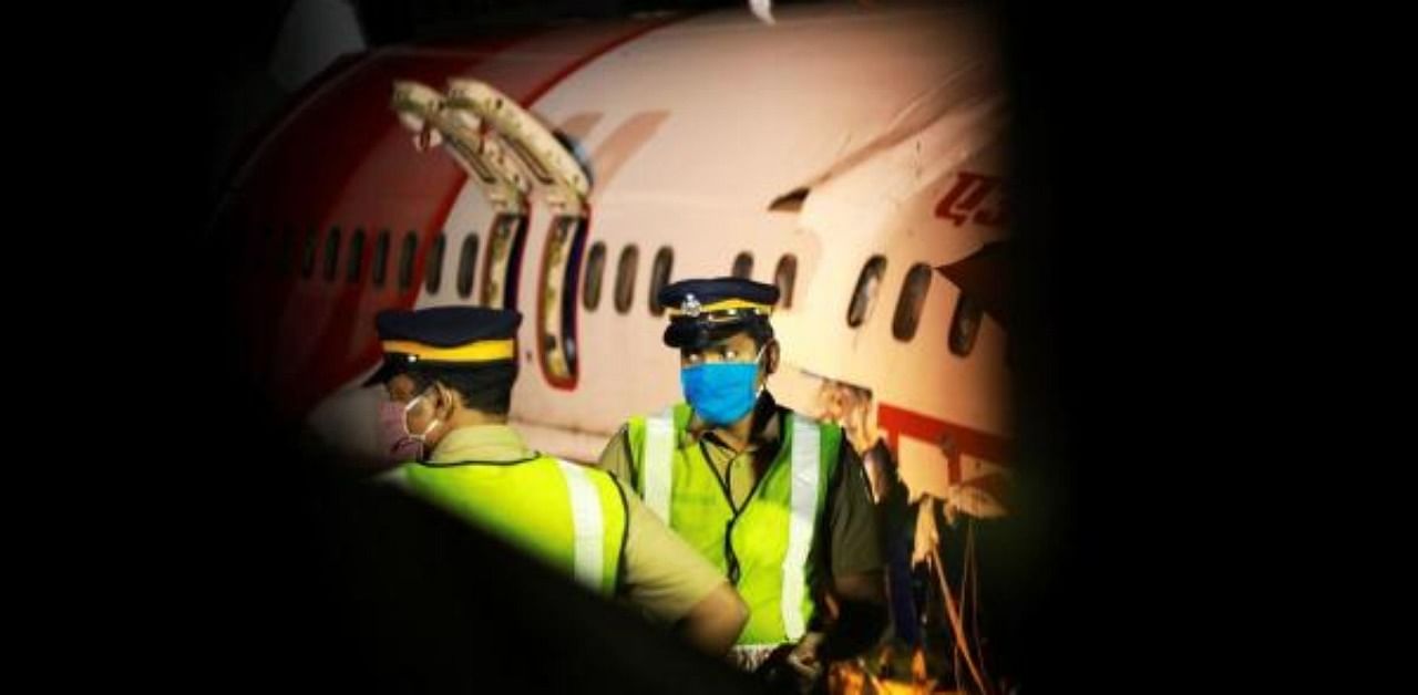 Security personnel stand guard in front of the wreckage from an Air India Express jet. Credit: AFP