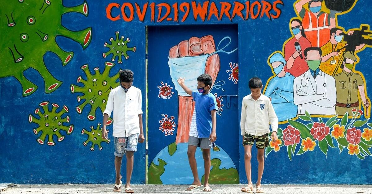  A youth (C) gestures as he walks with others past a mural dedicated to frontline workers fighting against the spread of the Covid-19, in Chennai on August 6, 2020. Credit: AFP Photo