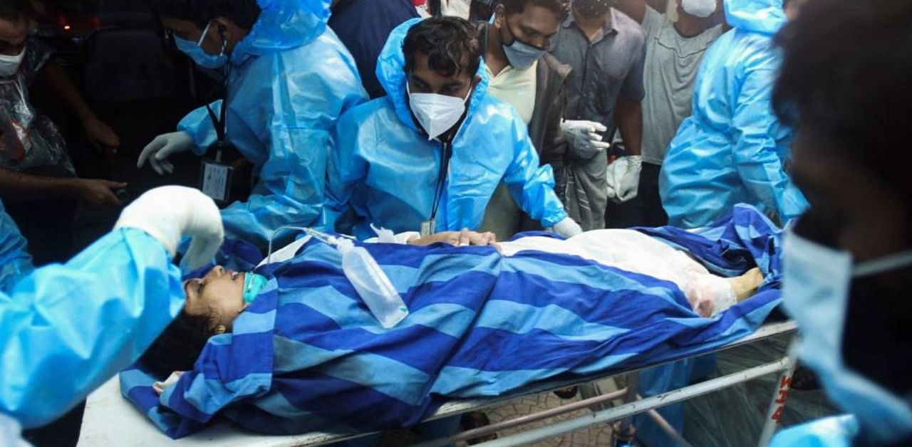 Health workers transfer an inured passenger on a stretcher to take her inside a hospital in Kozhikode, Kerela, after an Air India Express jet crashed by overshooting the runway at Calicut International Airport, on August 7, 2020. (AFP)