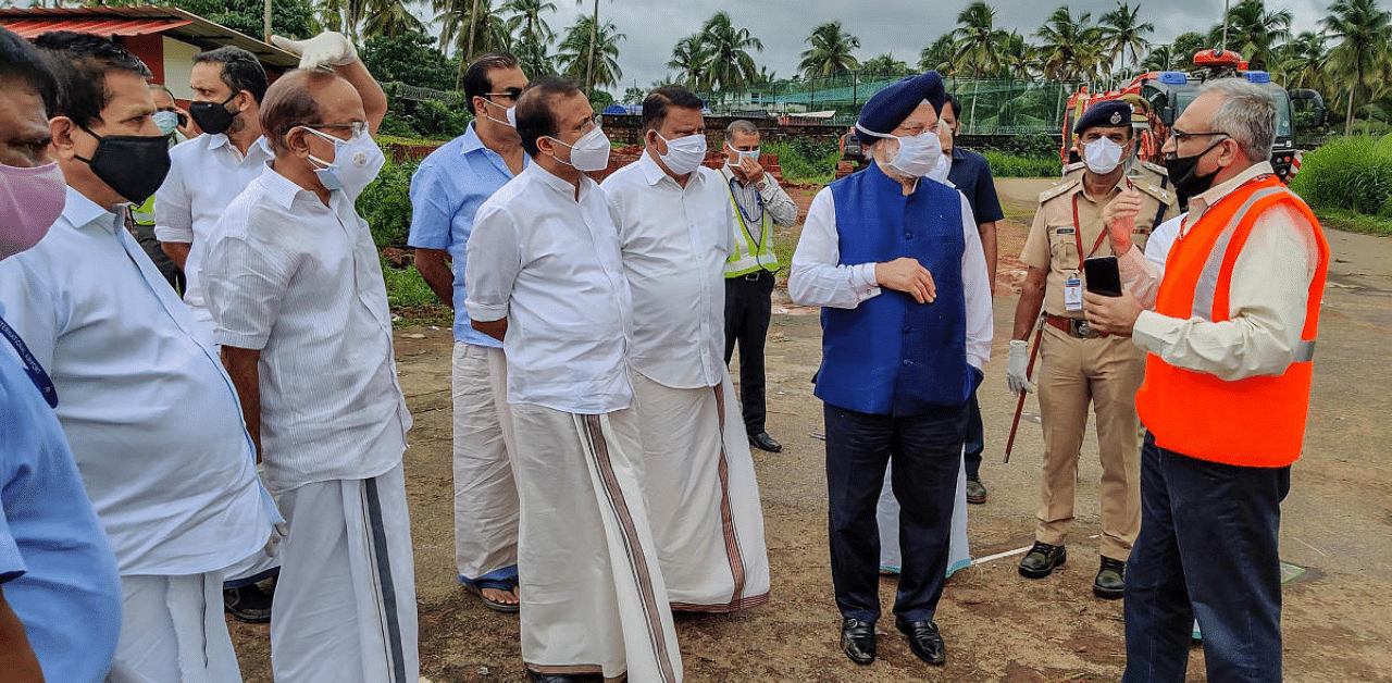 Union Civil Aviation Minister Hardeep Singh Puri enquires during his visit to the crash site of an Air India Express flight, en route from Dubai, after it skidded off the runway while landing, at Karippur in Kozhikode. Credit: PTI Photo