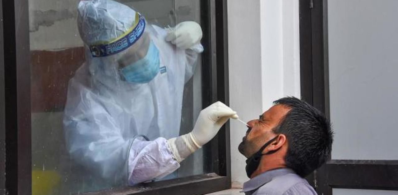 A health worker collects a swab sample from a shopkeeper for Covid-19 test. Credit: PTI Photo