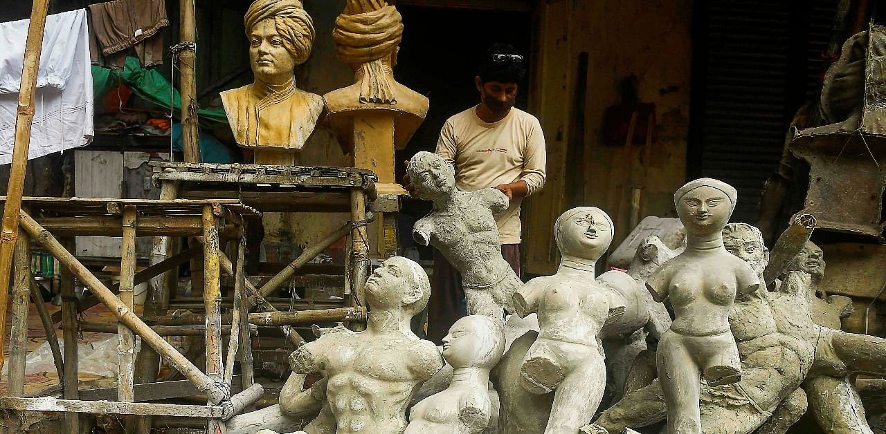 An artisan arranges partially finished statues at a roadside workshop during a complete lockdown in Kolkata. Credit: AFP