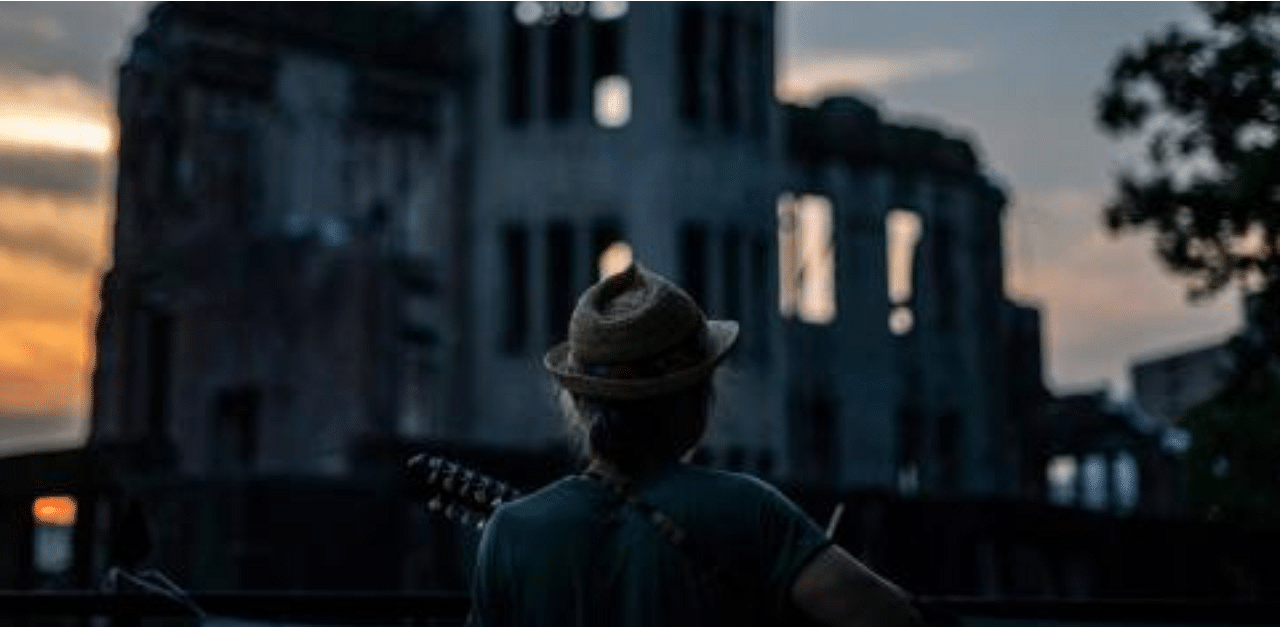 A man plays his guitar in front of in front of ruins of the Hiroshima Prefectural Industrial Promotion Hall, now commonly known as the atomic bomb dome, during sunset in Hiroshima. Credit: AFP Photo