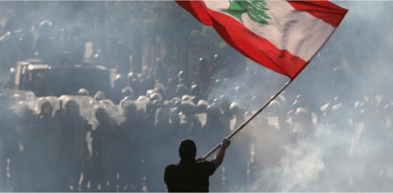 A demonstrator waves the Lebanese flag in front of riot police during a protest in Beirut, Lebanon. Credit: Reuters Photo