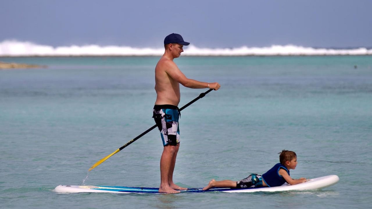 This file photo taken on August 30, 2012 shows a tourist operating a stand up paddle board at Muri beach on Rarotonga, the largest island in the Cook Islands. Credit: AFP