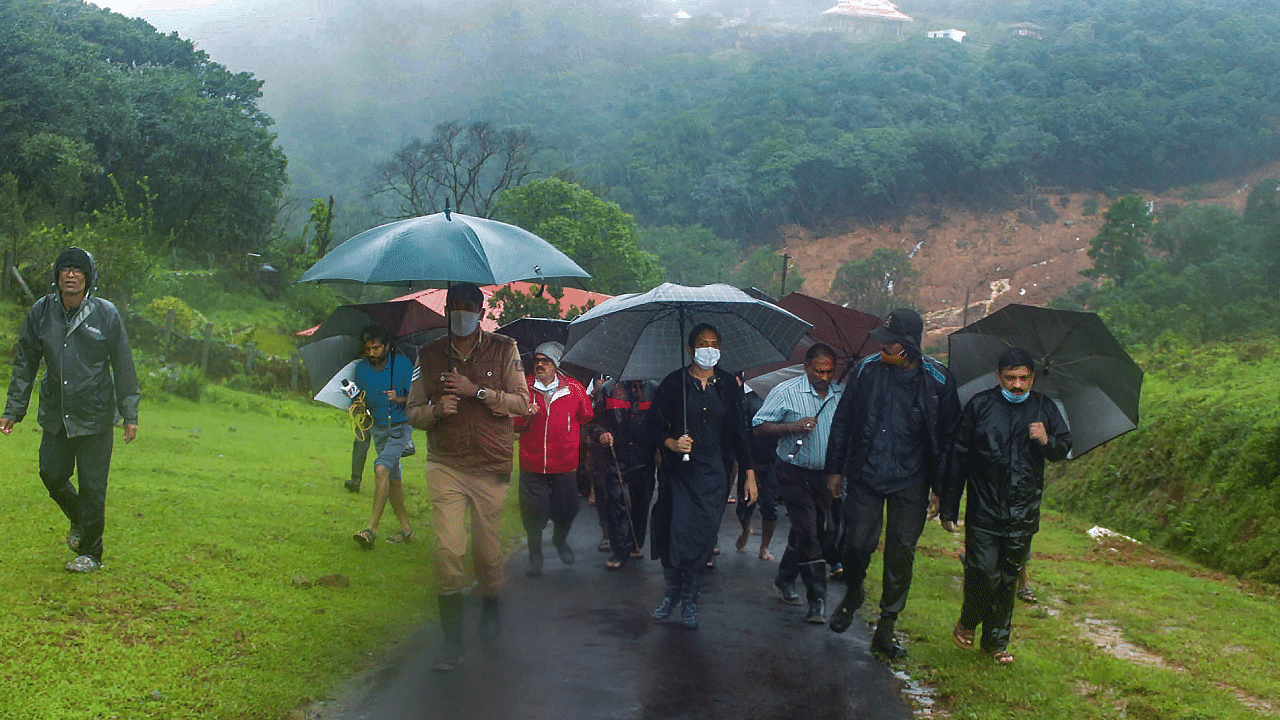 Officials walk towards the site of landslide on the foothills of the Brahmagiri Hills, during rainfall. Credits: PTI Photo