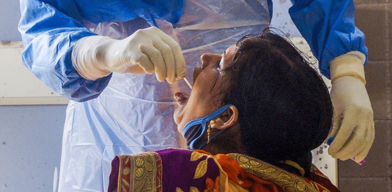 A medic collects a swab sample of a woman for Covid-19 test in Bhubaneswar. Credit: PTI Photo