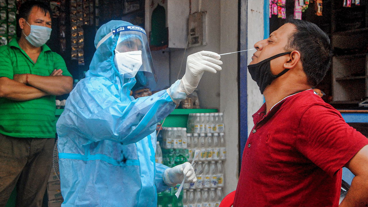 A health worker collects sample of a person for Covid-19 test via Rapid Antigen Testing, at Manipuri Basti in Guwahati. Credits: PTI Photo