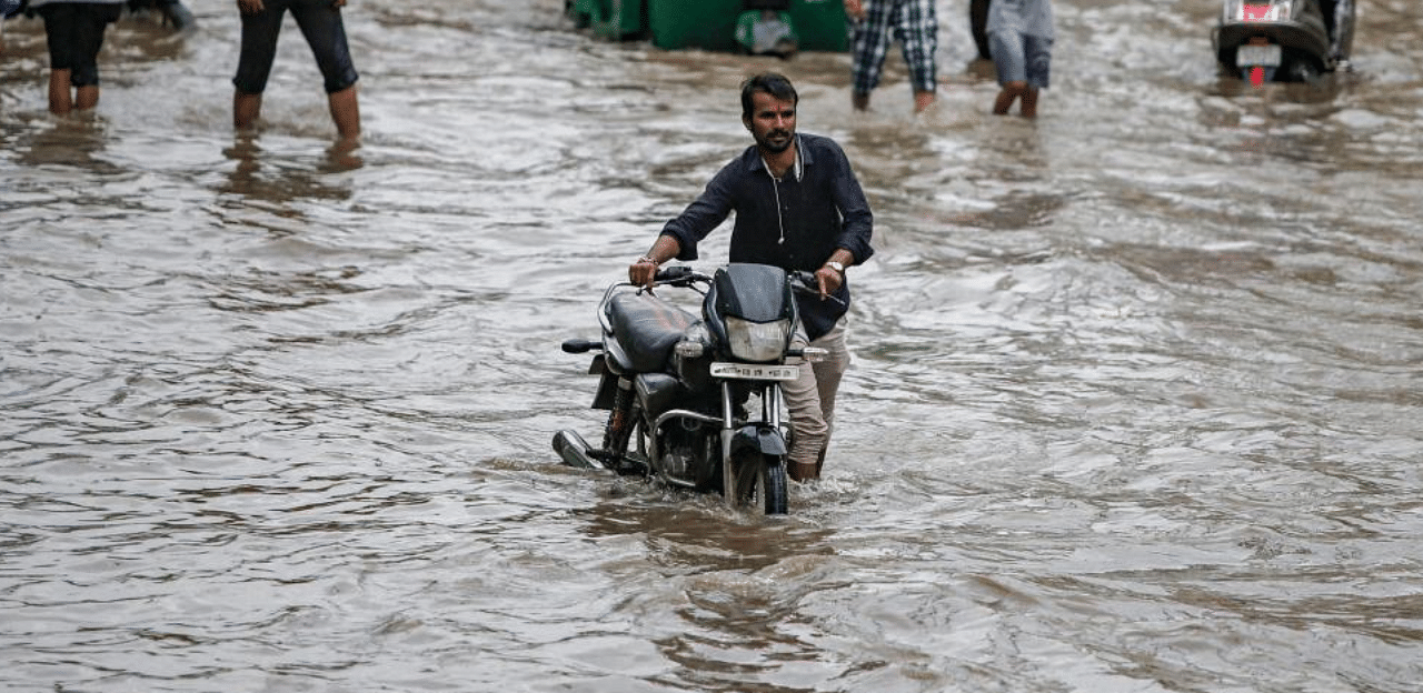 Commuters wade through a waterlogged street following heavy rains, in Ahmedabad, Tuesday, Sept. 10, 2019. Credit: PTI Photo