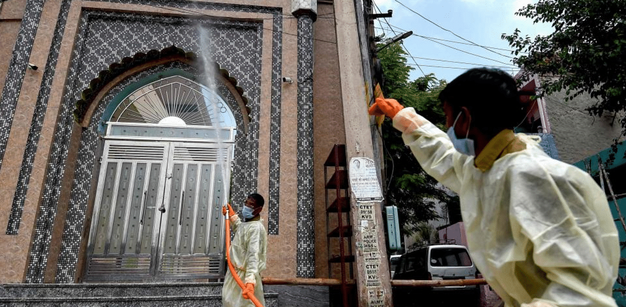 Municipal workers spray disinfectant solution to sanitise the exterior of a mosque in Faridabad. Credit: AFP File Photo