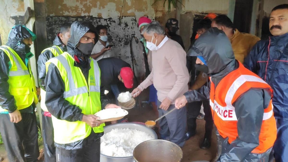 District In-Charge Minister V Somanna serves meals to the members of the rescue teams in Talacauvery.
