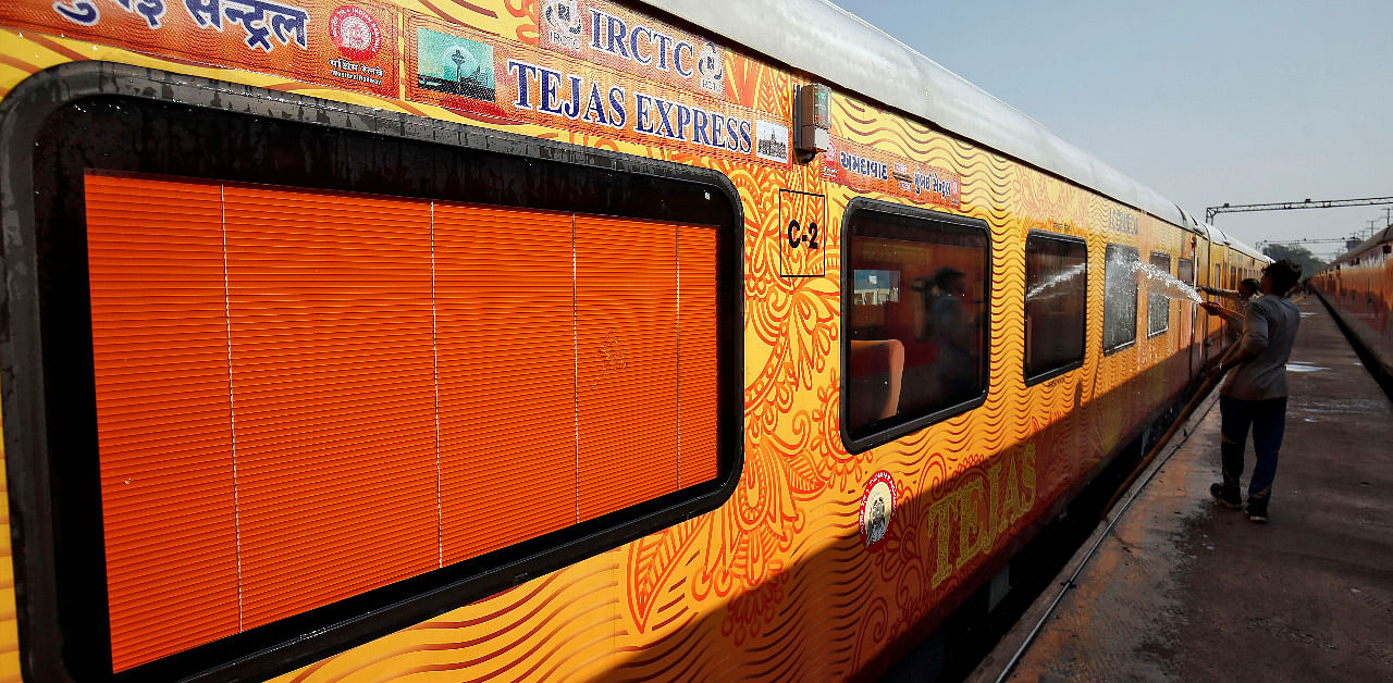 A man cleans the exteriors of a coach of India's first private train Tejas Express. Credit: Reuters Photo