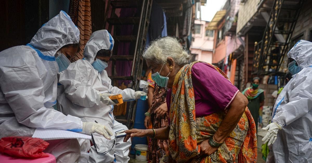  Health workers wearing Personal Protective Equipments (PPE) check the temperature and the oxygen level of an elderly resident during a coronavirus screening in the Dharavi slum, in Mumbai on August 11, 2020. Credit: AFP Photo