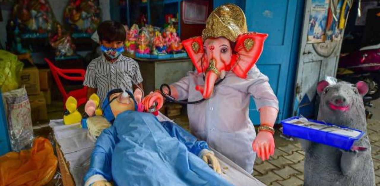 A boy stands near the Covid-19 worriers themed idols for Puja festivities at a workshop. Credit: PTI