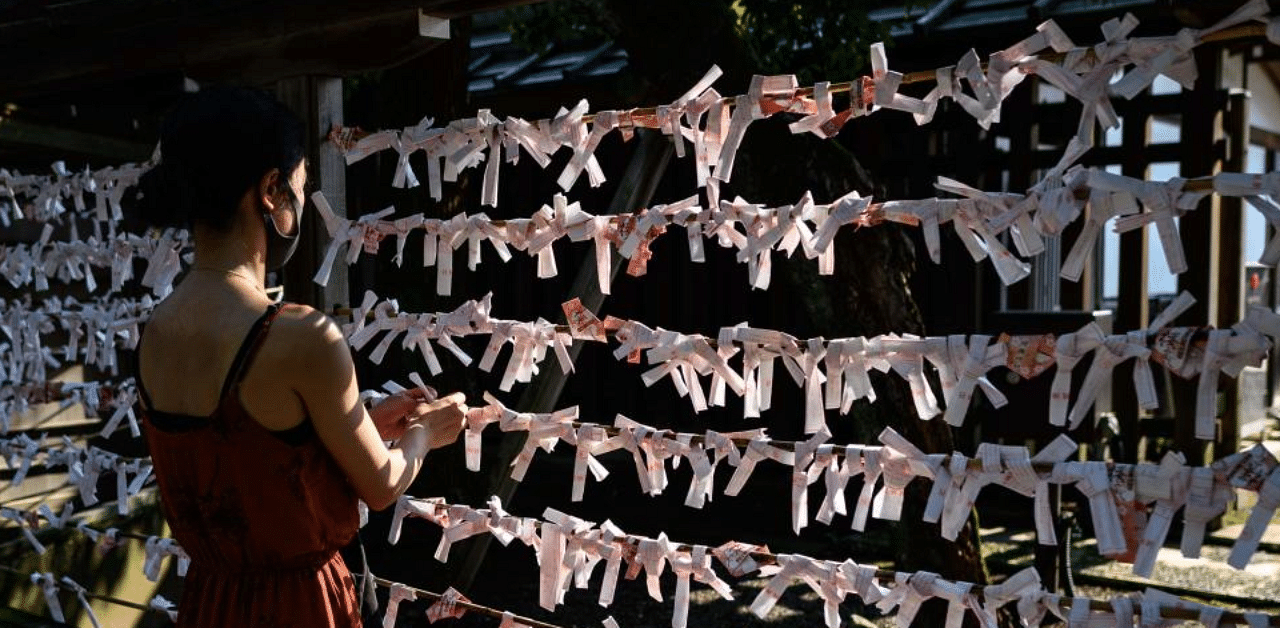 A visitor attaches a fortune telling slip of paper, also known as "omikuji", to a display during her visit to Yasukuni Shrine in Tokyo. Credit: AFP Photo