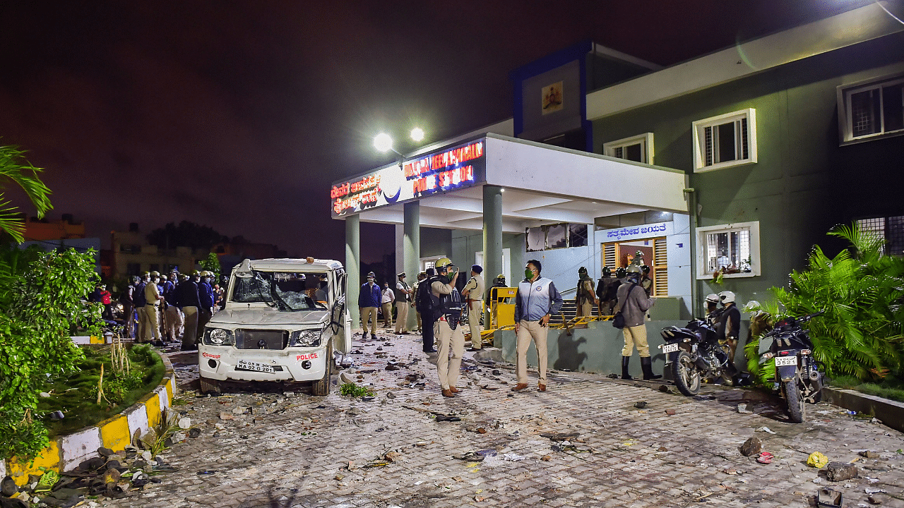 Police stand guard after a mob vandalised a police station following a social media post by a relative of a MLA, in Bengaluru. Credits: PTI Photo