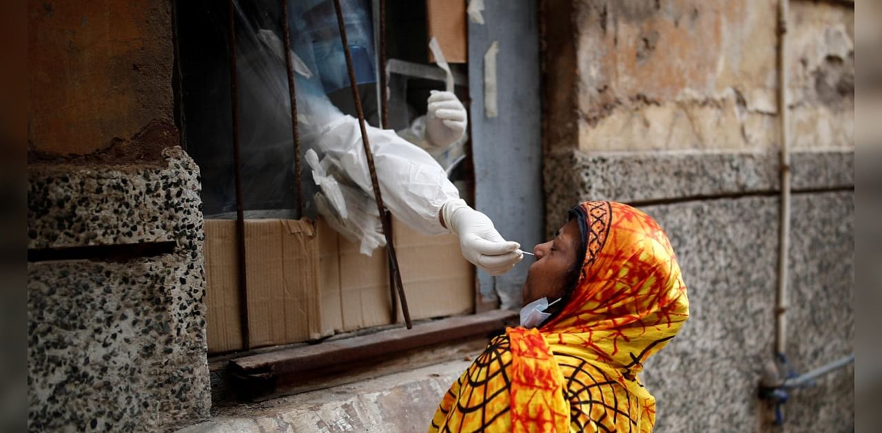 A health worker in personal protective equipment (PPE) collects a sample using a swab from a person at a local health centre to conduct tests for the coronavirus disease (COVID-19), amid the spread of the disease, in the old quarters of Delhi. Credit: Reuters Photo