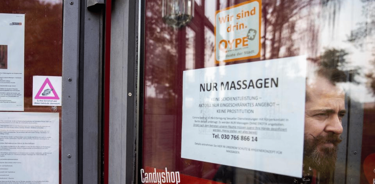 Manager Aurel Johannes Marx is seen at the entrance with notes informing clients the new rules at the Candy Store brothel in Berlin on August 10, 2020 amid the Covid-19 corona virus pandemic. Credit: AFP Photo