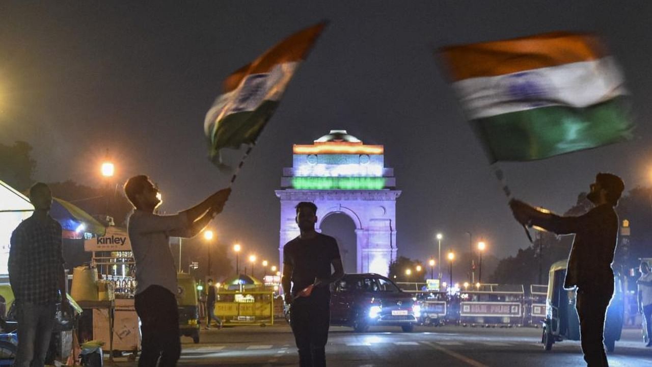  People at India Gate wave Indian national flags on the eve of Independence Day, in New Delhi. Credit: PTI