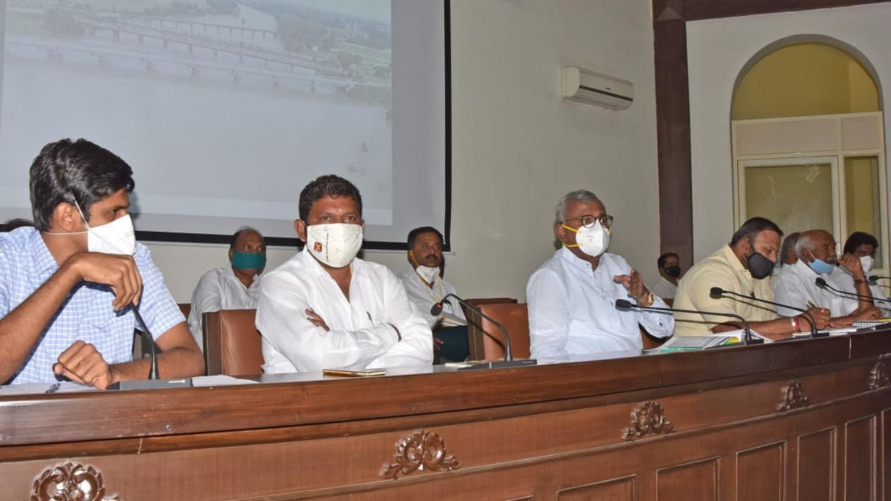 District in-charge Minister S T Somashekar addresses a meeting at the Zilla Panchayat in Mysuru on Friday. Deputy Commissioner Abhiram G Sankar and MLA H P Manjunath are seen.