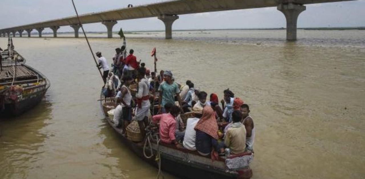 Villagers travel through the swollen Ganga river on a boat, in Patna. Credit: PTI