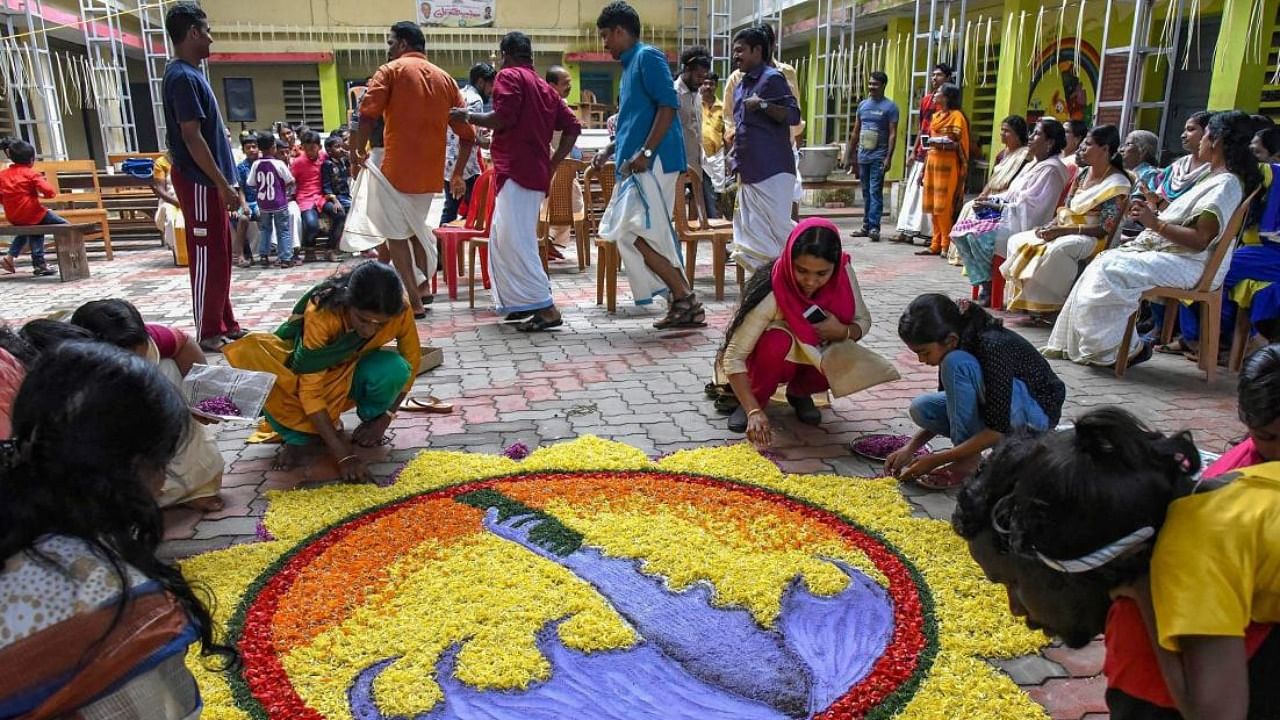 Women make a 'rangoli' as they celebrate 'Onam' at a flood relief camp in Kochi. Credit: PTI/file