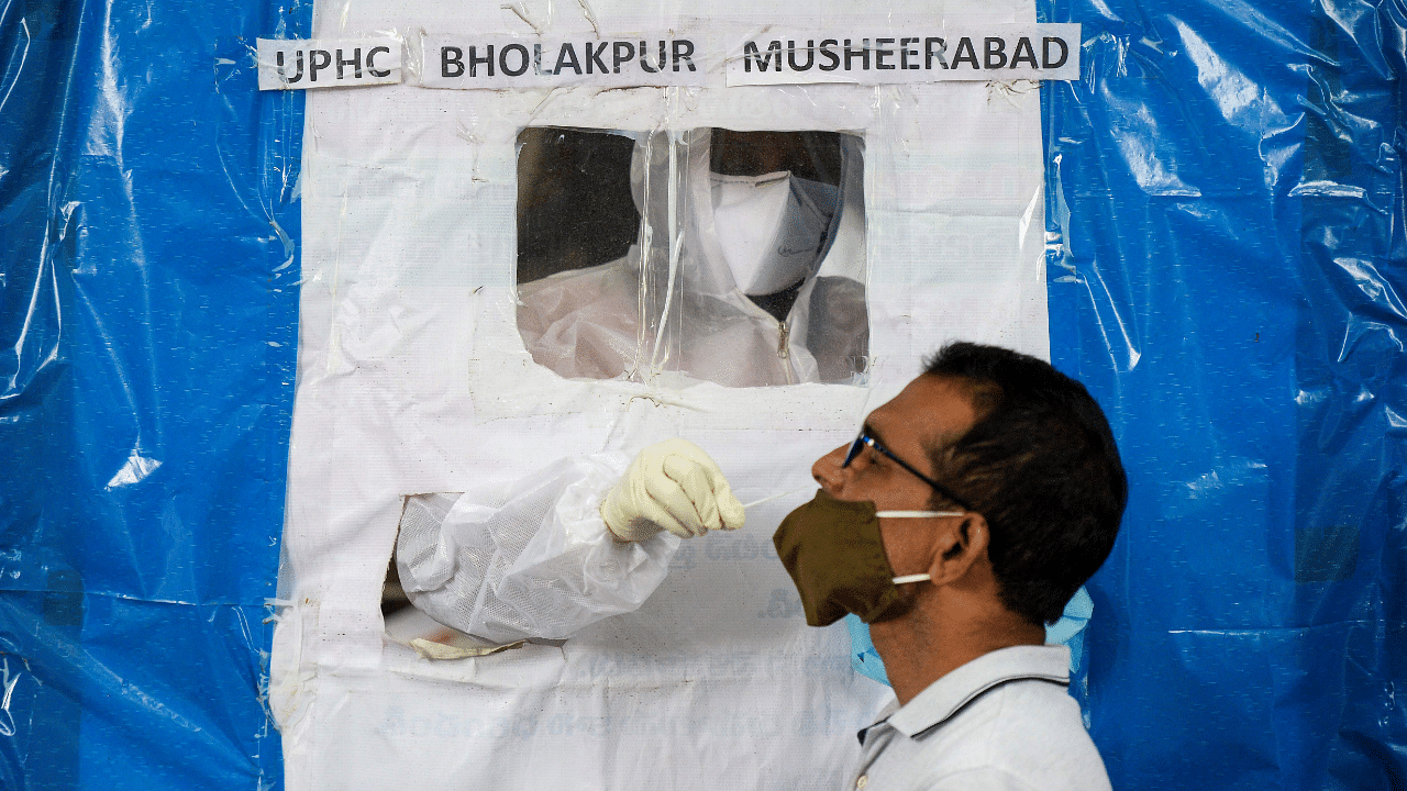 A health worker collects a swab from a resident at a makeshift free Covid-19. Credits: AFP Photo