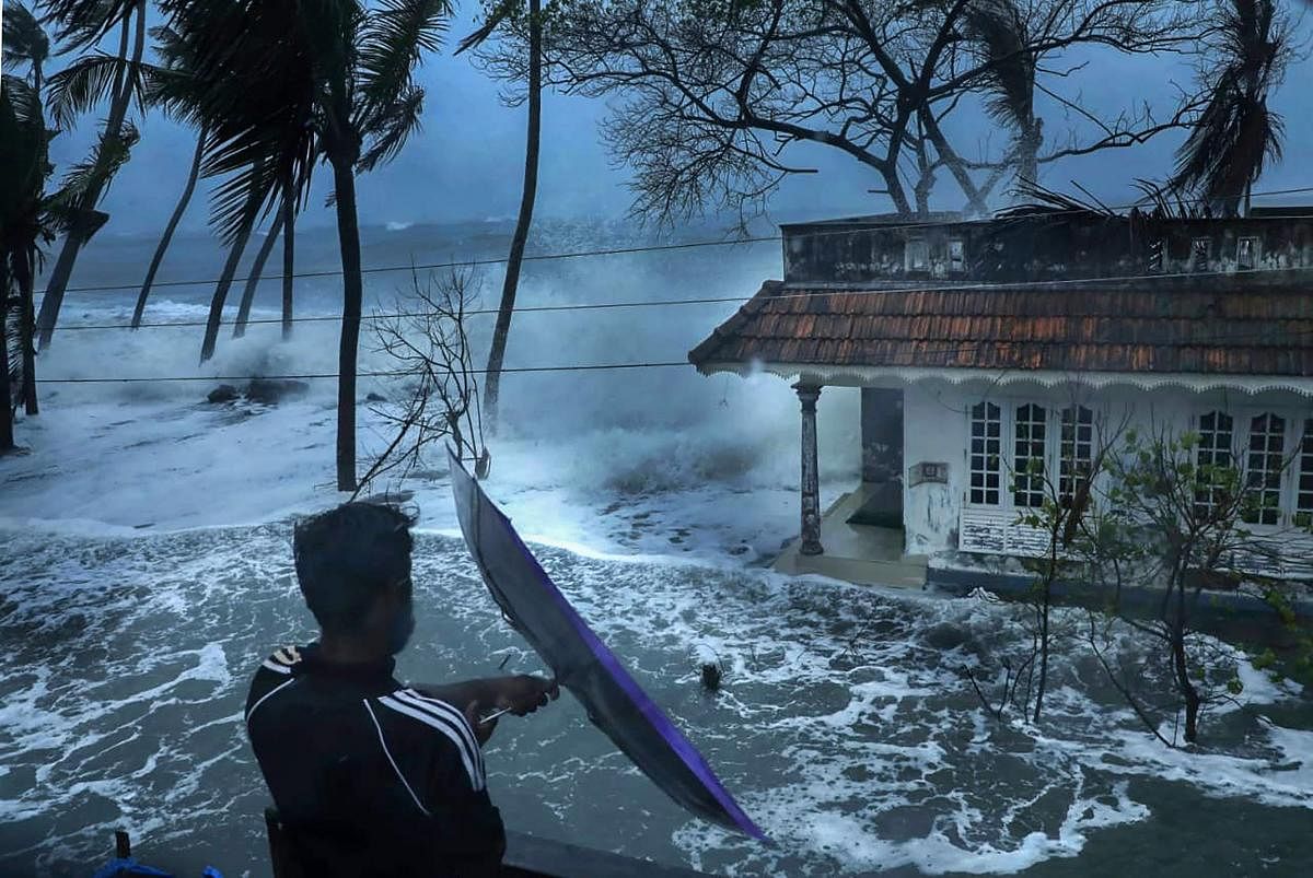 Kochi: A man attempts to open an umbrella during a stormy weather as sea water enters Chellanam area following heavy rainfall, in Kochi, Friday, Aug. 7, 2020. (PTI Photo)(PTI07-08-2020_000204B)