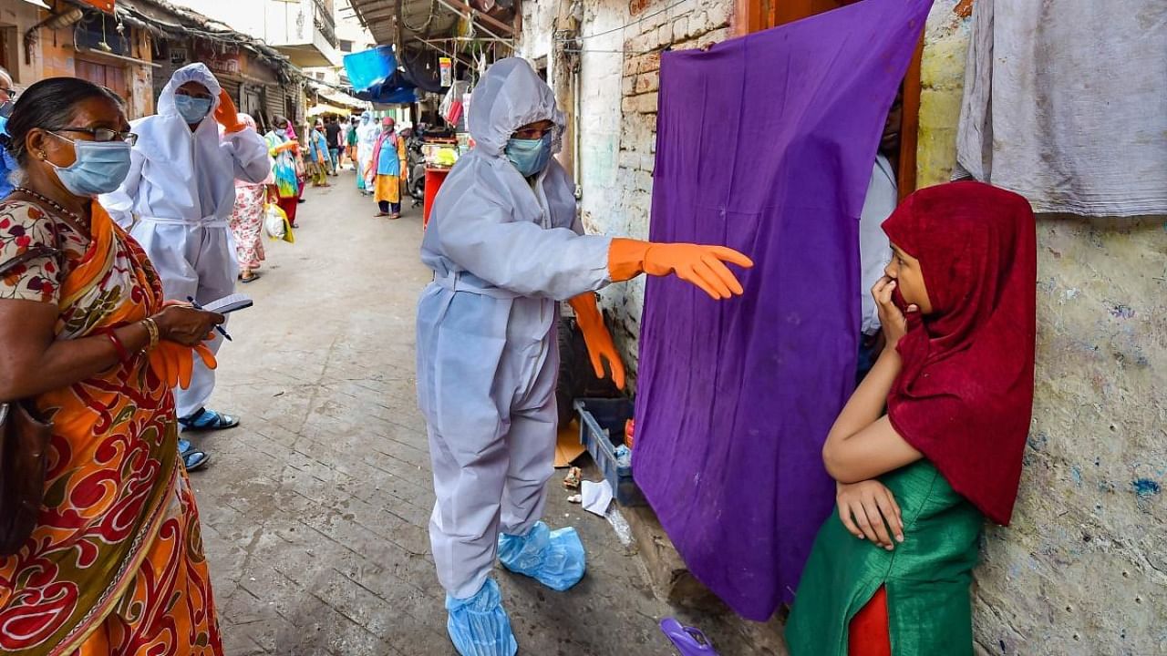 Health workers wearing protective suits interact with slum dwellers during a house-to-house health survey at Belgachia. Credit: PTI/file photo