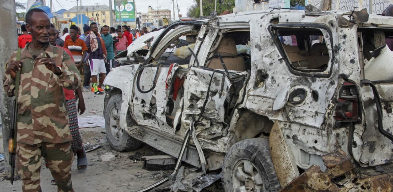 A member of the security forces walks past a wrecked vehicle outside the Elite Hotel in Mogadishu, Somalia Monday, Aug. 17, 2020. (AP)