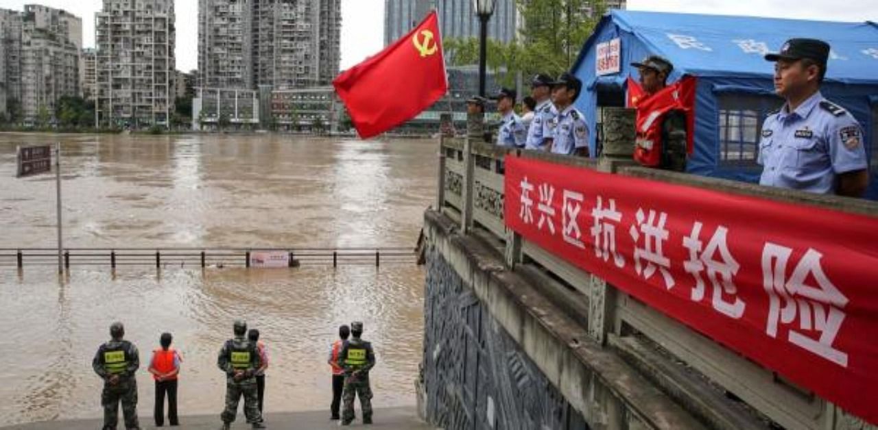 Police officers stand guard along the swollen Tuojiang River following heavy rain in Neijiang in China's southwestern Sichuan. Credit: AFP Photo