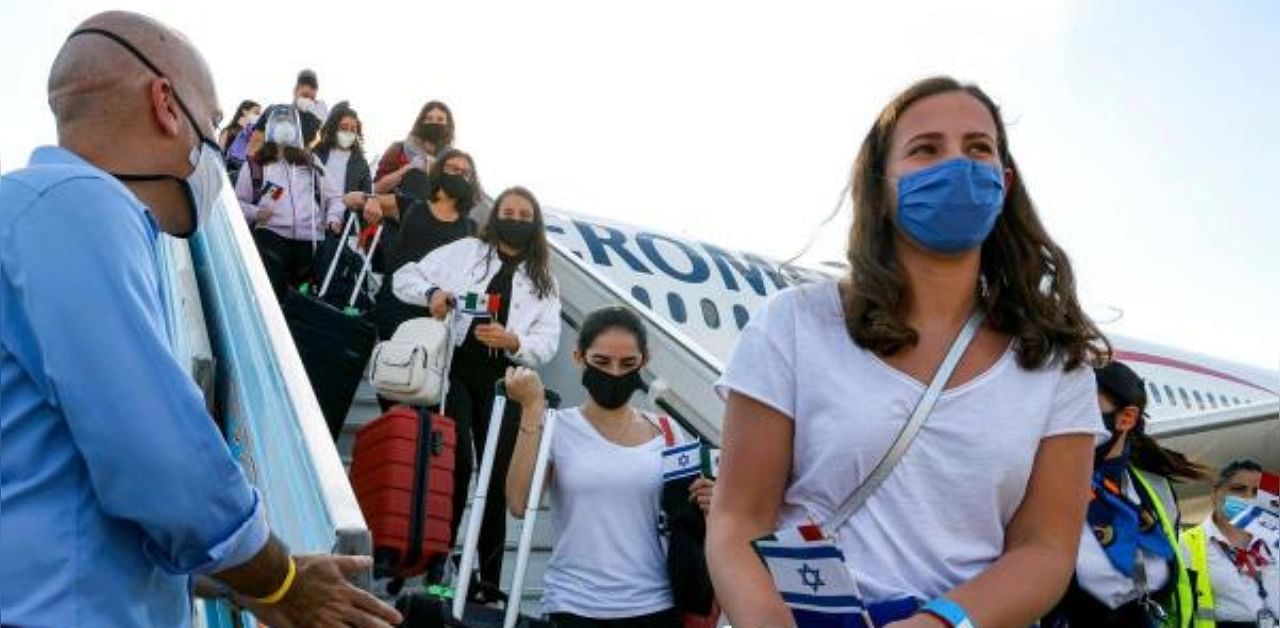 People, mask-clad due to the COVID-19 coronavirus pandemic, descend a ramp as they disembark from a plane. Credit: AFP