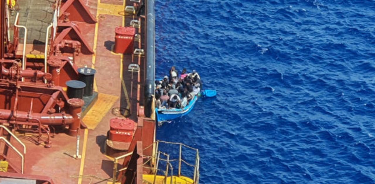 Migrants sit in a boat alongside the Maersk Etienne tanker off the coast of Malta. Credit: Reuters