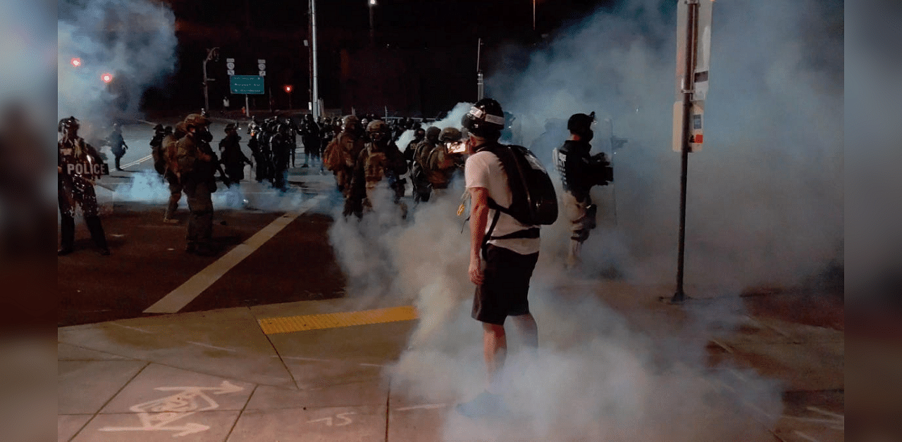 A member of the media stands amid tear gas used by police officers to clear protesters near an Immigration and Customs Enforcement centre in Portland. Credit: Reuters