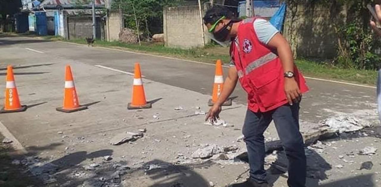 A Red Cross member inspecting a crack on a road caused by a 6.6-magnitude earthquake that hit Uson town in Masbate province. Credit: AFP