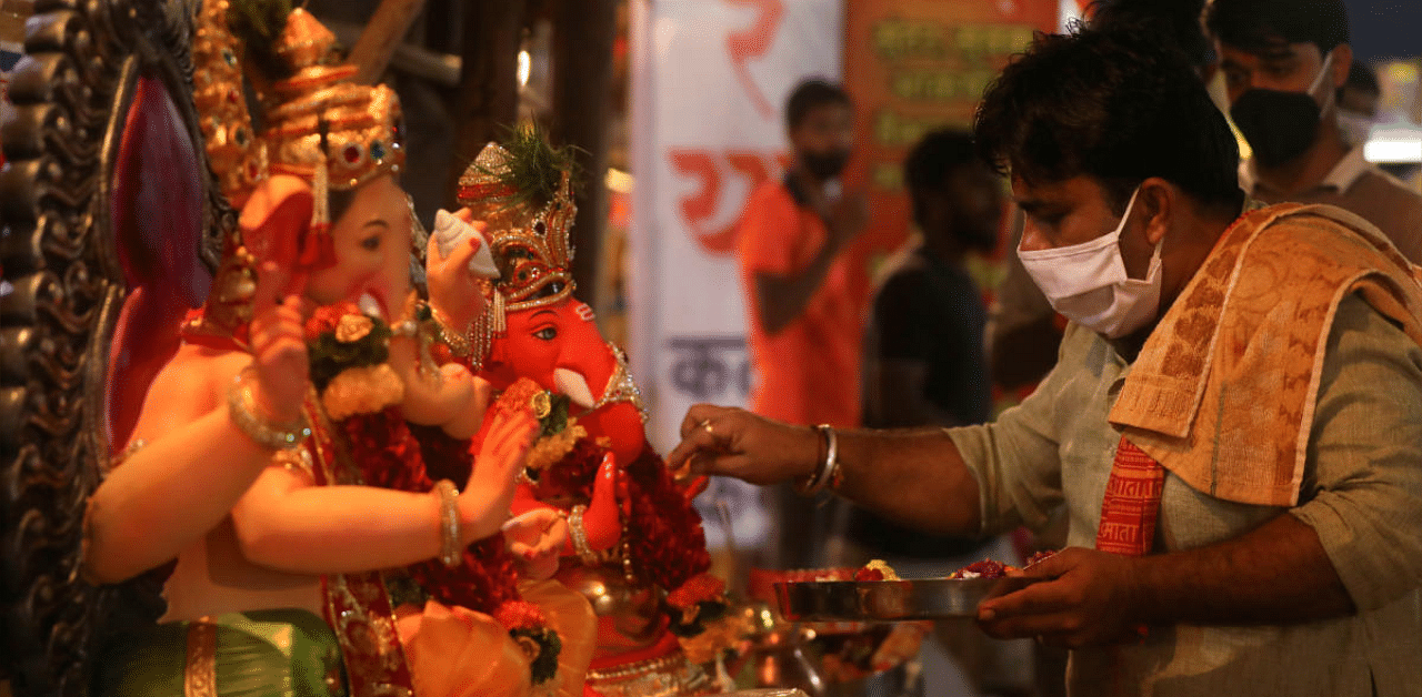 A priest wearing a protective face mask conducts a puja in front of Lord Ganesha. Credit: Reuters