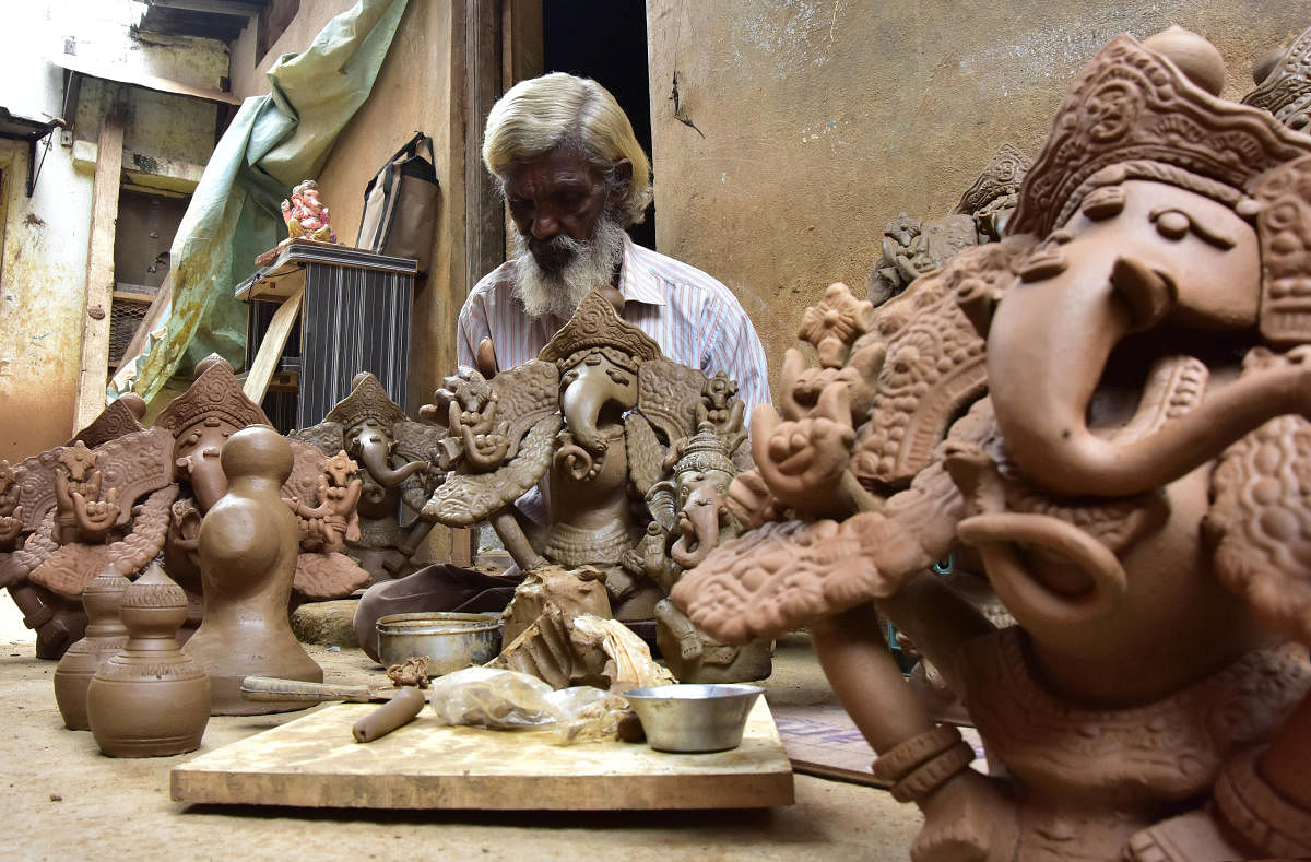 An artist gives final touches to his eco-friendly Ganesha idols at Pottery Town on Thursday. DH PHOTO/Irshad Mahammad