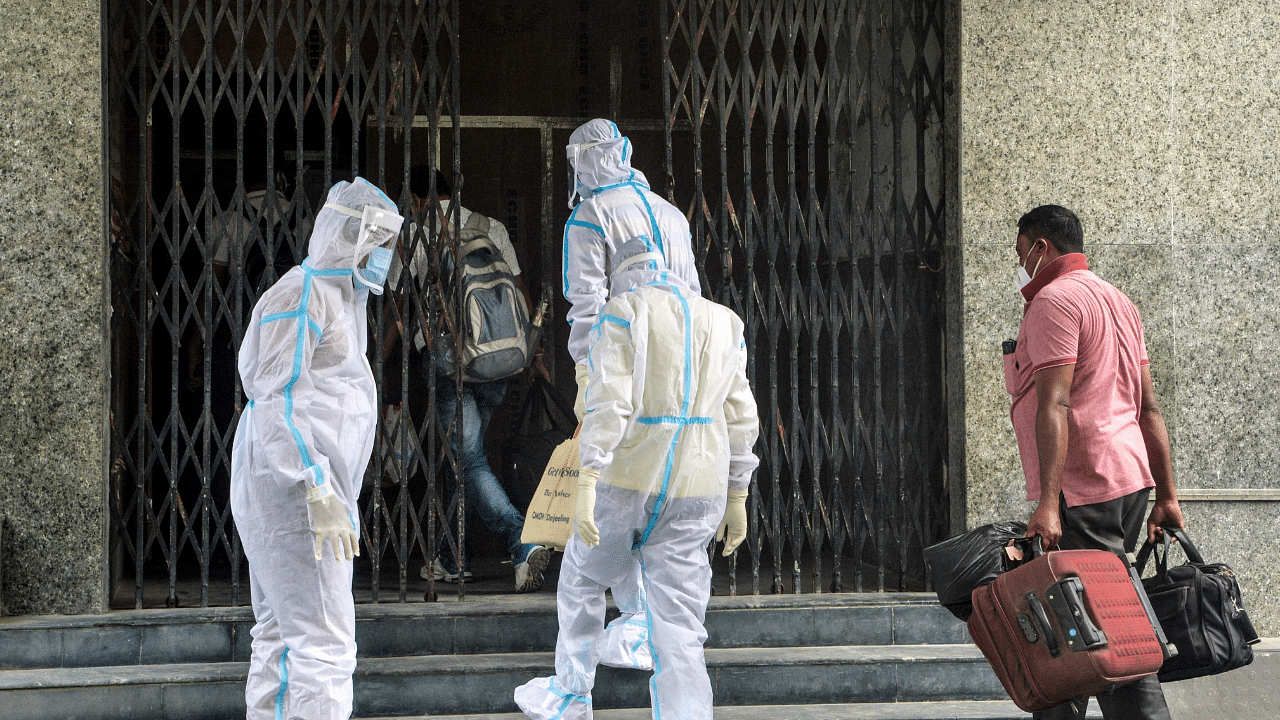 Health workers wearing Personal Protective Equipment (PPE) suits guide asymptomatic Covid-19 patients to the entrance of the Siliguri Indoor Stadium. Credits: AFP Photo