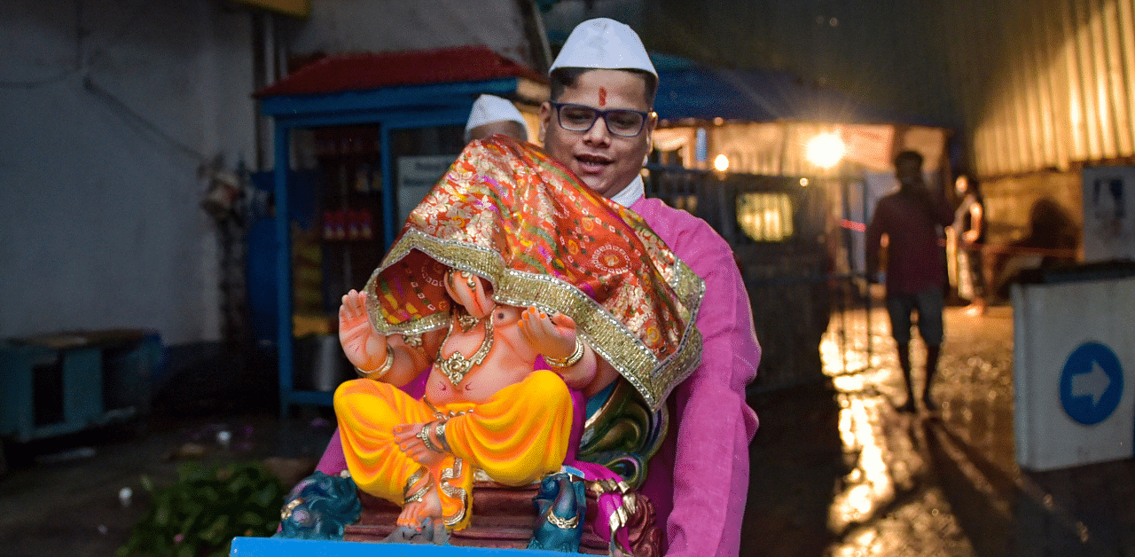 A devotee carries a Ganesh idol to his home on the eve of Ganpati festival, at Dadar in Mumbai. Credit: PTI Photo