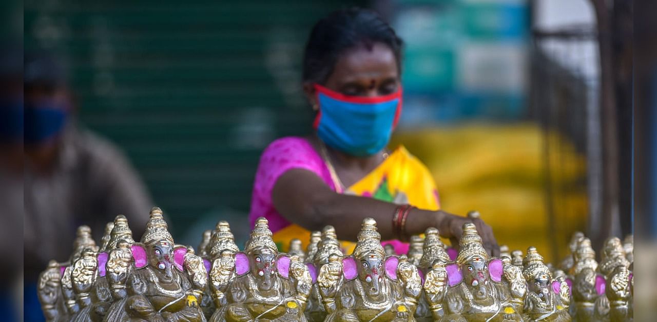 A vendor arranges idols of Lord Ganesh as she waits for customers on the eve of Ganesh Chaturthi festival, at Mylapore in Chennai, Friday, Aug 21, 2020. The state government decided not to allow the installation of Lord Ganesh idols in public places and processions or their immersion in water bodies following the coronavirus outbreak. Credit: PTI Photo