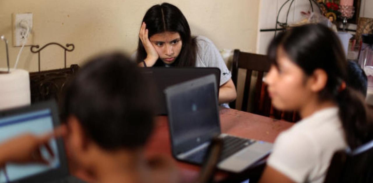 Students work on school-issued computers, at their home in Los Angeles. Credit: Reuters