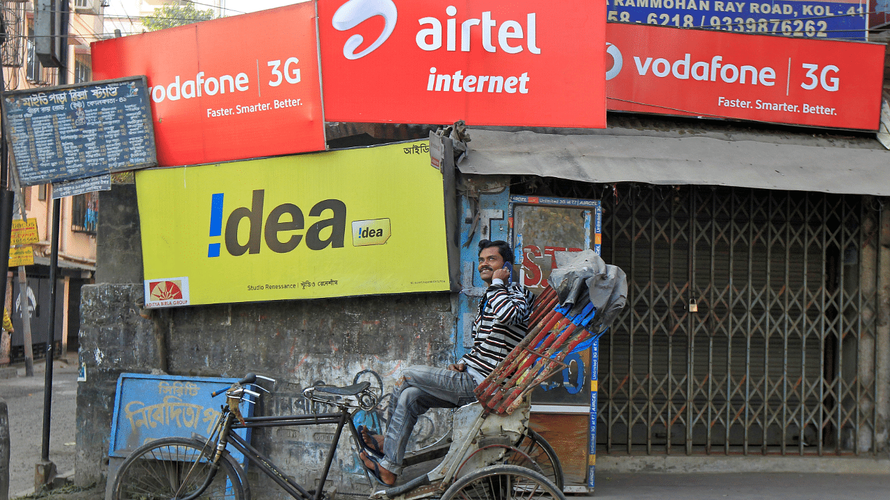 A rickshaw puller speaks on his mobile phone in front of advertisement billboards belonging to telecom companies. Credits: Reuters Photo