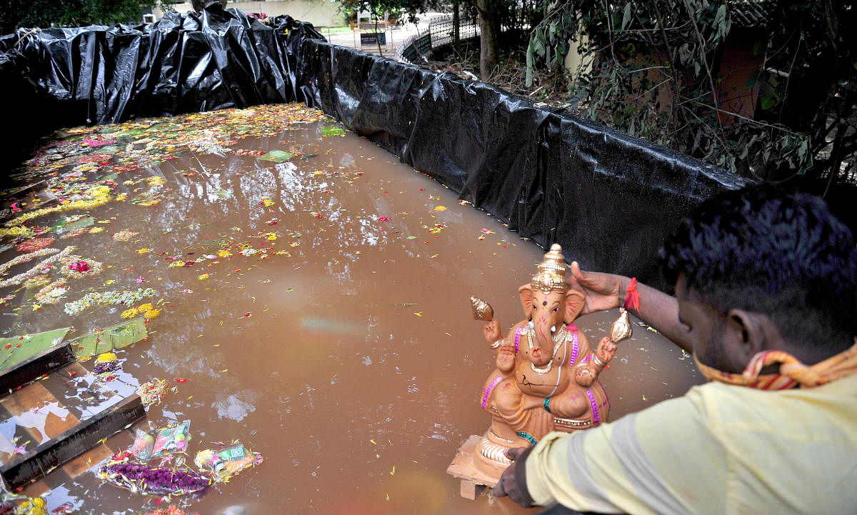 A BBMP worker immerses a Ganesha idol handed over by a citizen at a mobile tank near Sankey Tank in Bengaluru on Sunday. DH PHOTO/PUSHKAR V