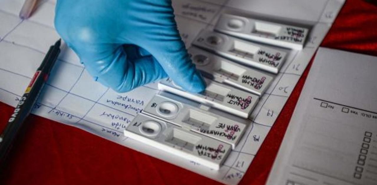 A health worker collects samples for antigen tests from nasal swabs of residents during a coronavirus screening. Credit: AFP