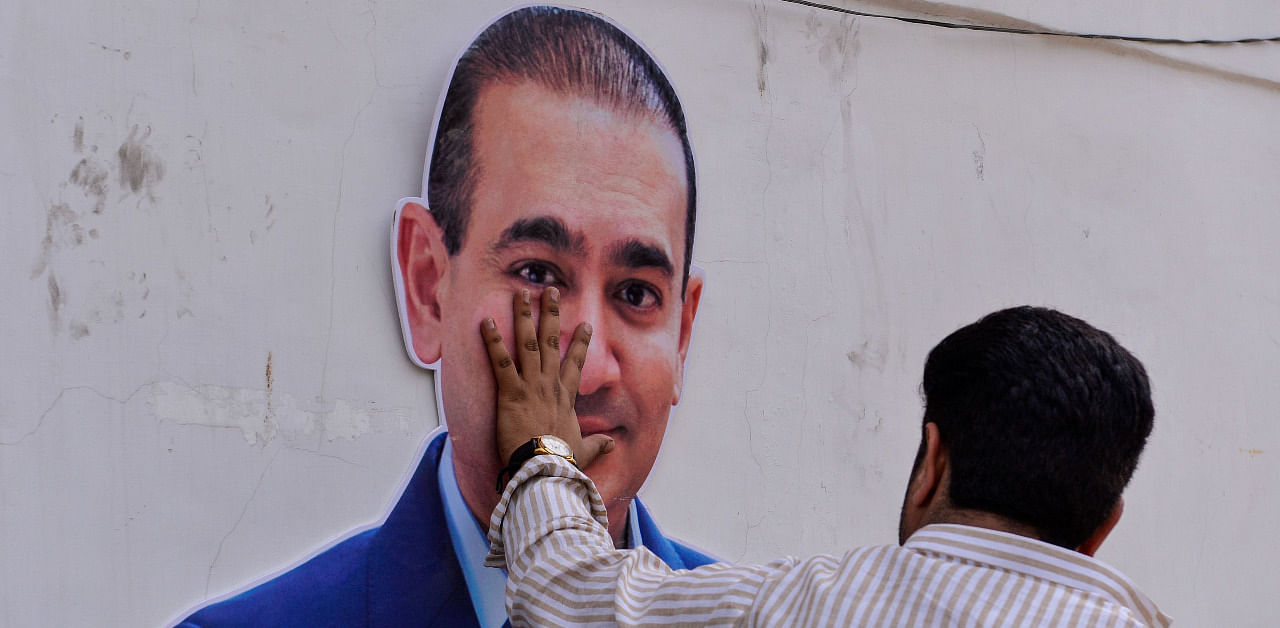 A man keeps his hand on the face of a cut out of billionaire jeweller Nirav Modi during a protest in New Delhi. Credit: AFP File Photo