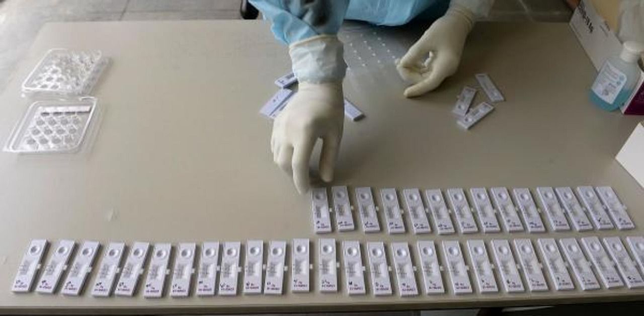 A health worker wearing personal protective equipment (PPE) arranges swab samples collected at a free coronavirus testing centre. Credit: AFP