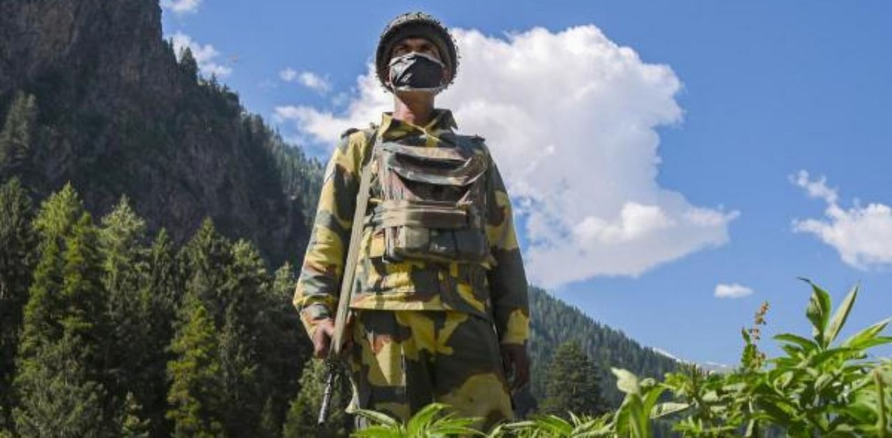 A Border Security Force (BSF) personnel wears a mask, standing guard along the Srinagar-Leh National highway. Credit: PTI