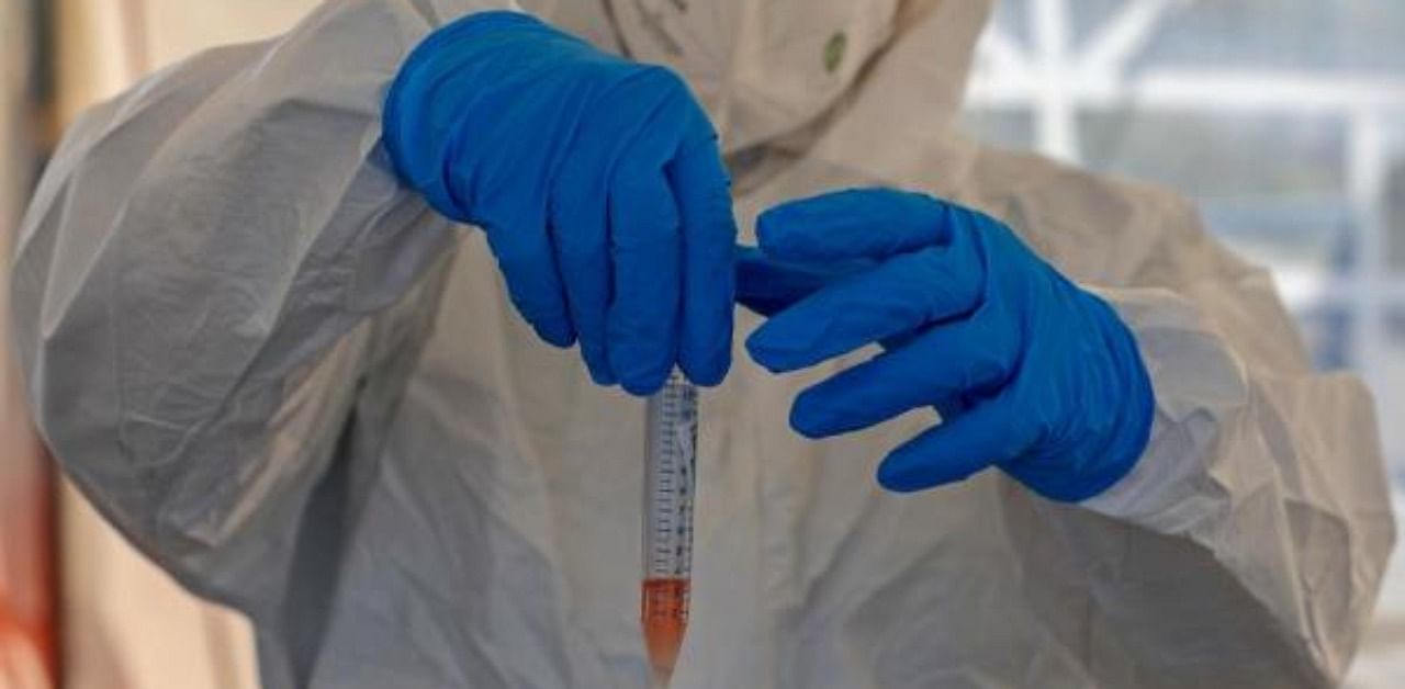A paramedic holds a swab tube at a drive-thru testing service for coronavirus. Credit: AFP