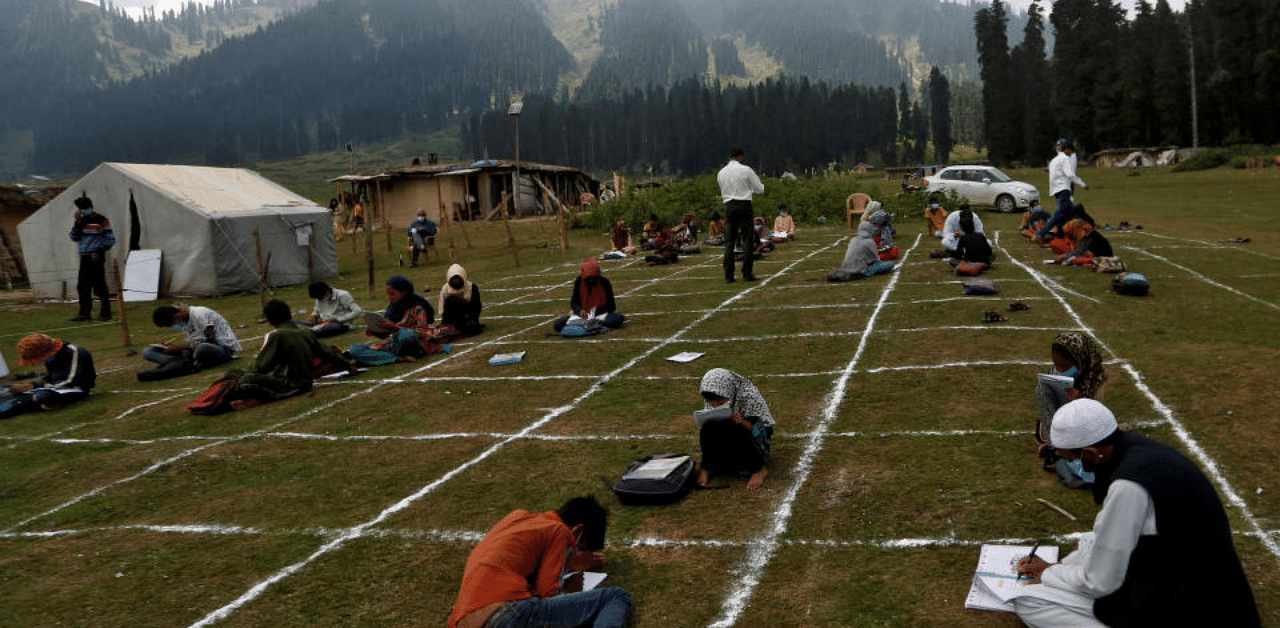 Teachers and children, who do not have access to internet facilities, sit on marked areas to maintain social distancing during their open-air classes after schools were closed following the coronavirus outbreak, at the scenic Doodhpathri in central Kashmir's Budgam district August 24, 2020. Credit: Reuters File Photo